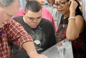 Michael Dennis listens carefully as Peter Doherty explains the use of the printing equipment.