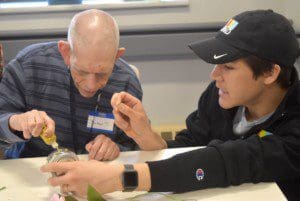 A KIND volunteer asssited Michael Tirotta with decorating a mason jar flowerpot
