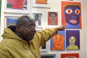 Wade Doby points to a few of his self portraits, which were part of the collective exhibition