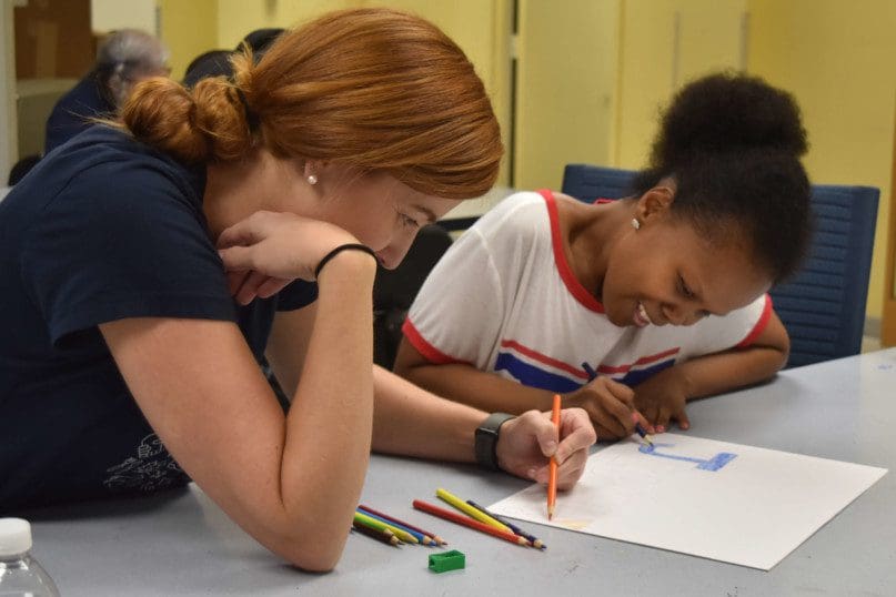 Ella Bernadez and a Salesfroce volunteer make a poster for the Day Services Track and Field Meet