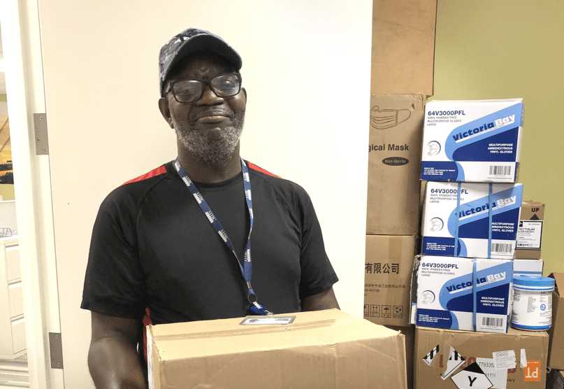 Samuel Joseph, Office Services Clerk, holds a box of personal protective equipment