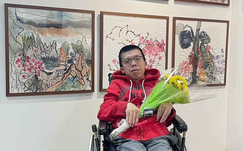 Bin Feng poses in front of his art pieces.