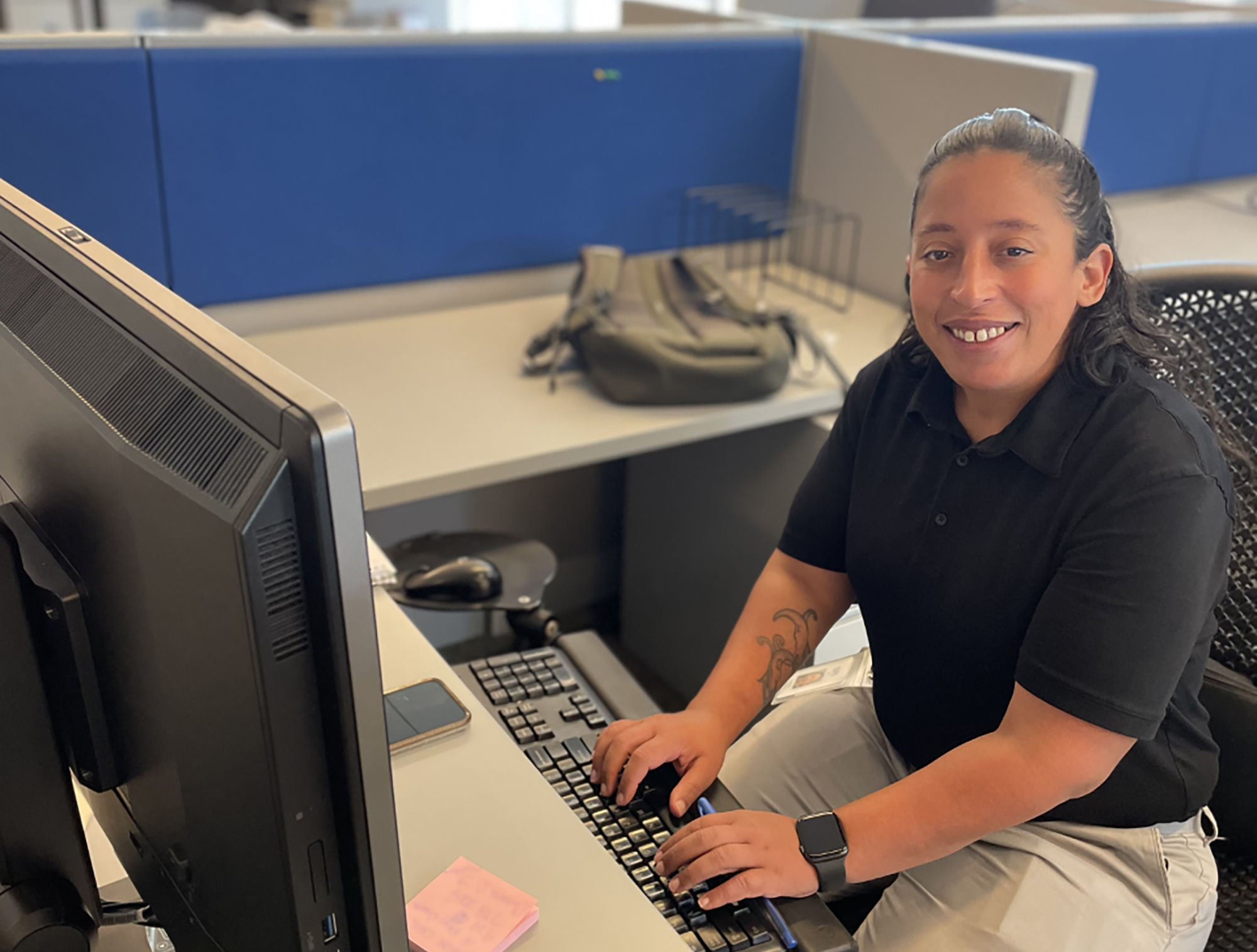 A young woman types on a keyboard while seated at her cubical desk, as an intern working through AHRC NYC's Partnership for Inclusive Internships