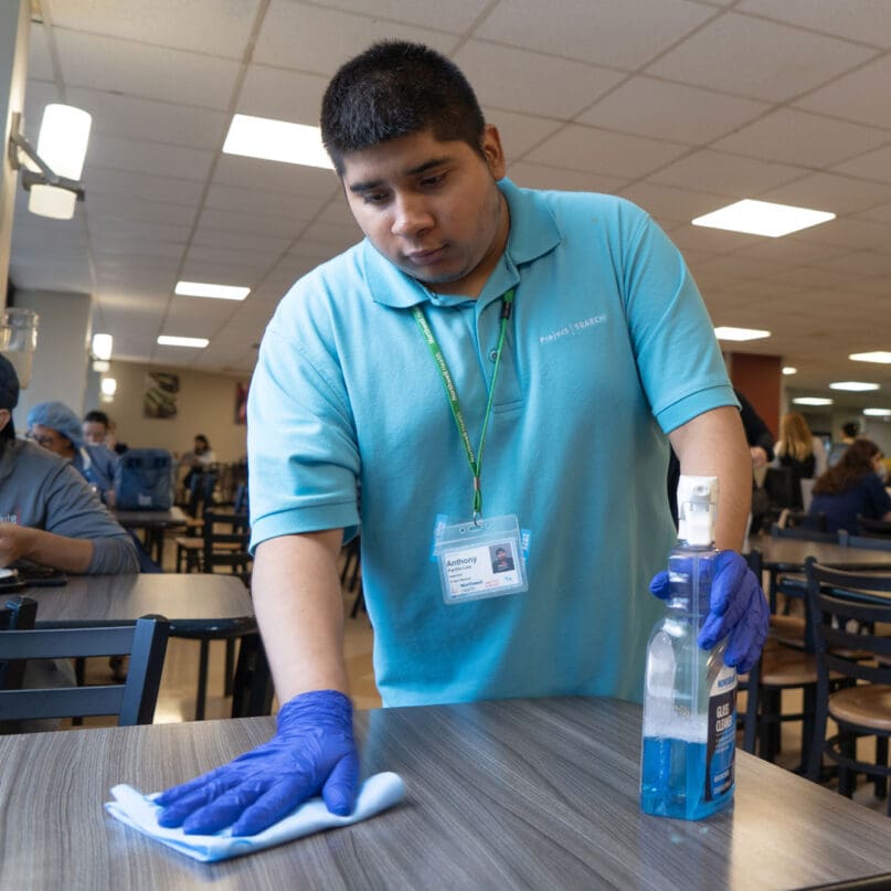 A Project SEARCH intern cleans a cafeteria table at Staten Island University Hospital