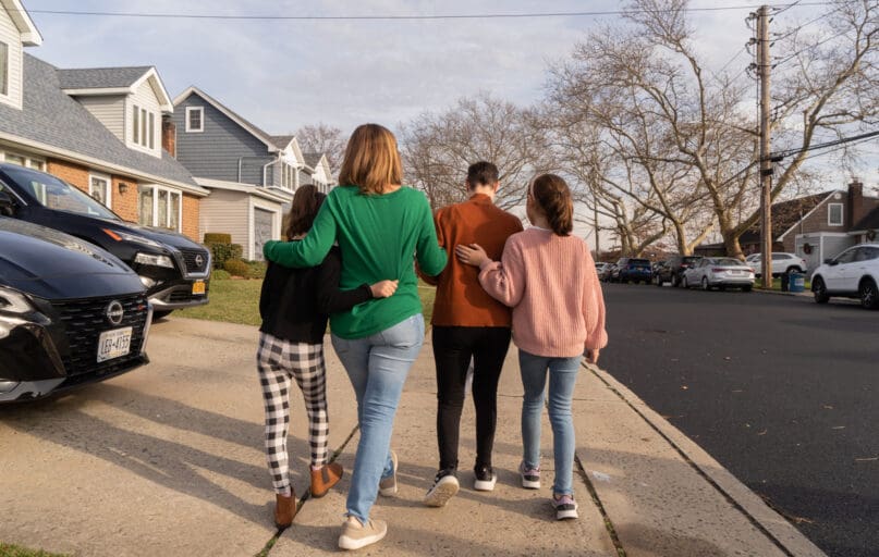 Four members of a family walk away on a neighborhood sidewalk, evoking AHRC NYC's Family Education Series Guardianship and Future Care Planning