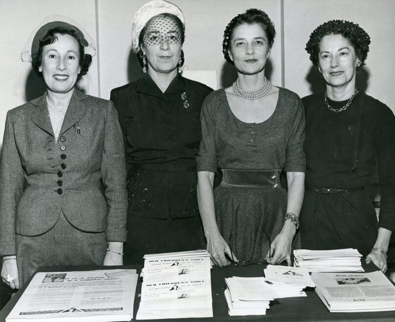 Four women from the Blue Feather Auxilliary standing in front of a table with pamphlets.