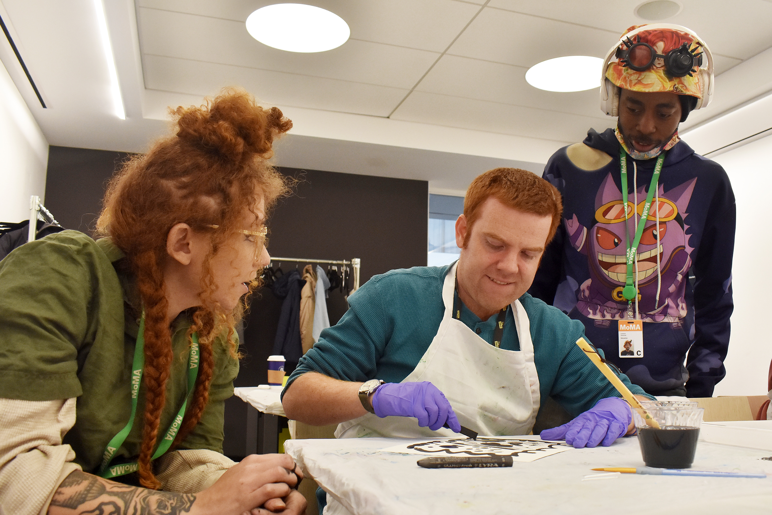 Lineton Gilchrist and Dounia Bendris observe as Brendan Berry creates during the MoMA workshop