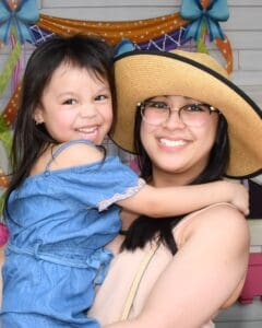 A mother holds her daughter as they smile